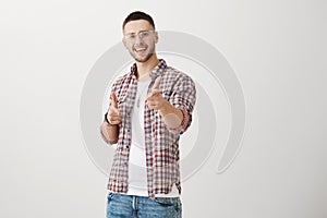 You caught me with your charm. Indoor shot of positive attractive young man with bristle, pointing at camera with index