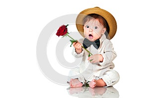 Emotional surprised toddler boy in retro, bow-tie hat and with red rose on white background.
