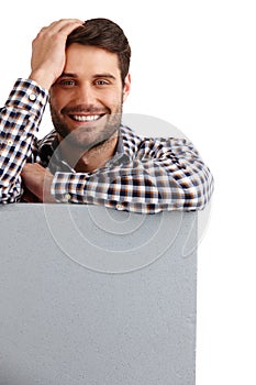 You couldnt ask for a better ad placement. Studio portrait of a handsome young man leaning on a blank placard isolated