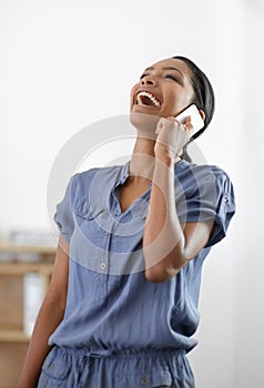 You crack me up. A happy young ethnic woman throwing her head back in laughter while on the phone.