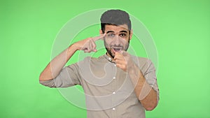 Are you crazy? Displeased brunette man making stupid gesture with finger near head and pointing to camera, taunting you.