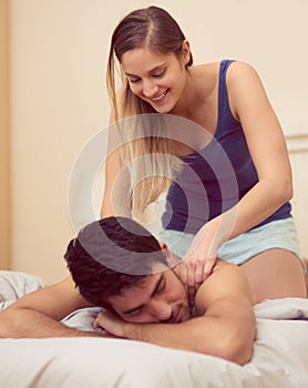 You deserve a massage, my love. a happy young woman giving her boyfriend a back massage in bed.