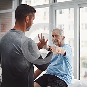 You dont have to live in pain. a young male physiotherapist assisting a senior patient in recovery.