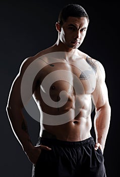 You dont need fancy tools to sculpt the perfect body. an athletic young man posing shirtless against a dark background.