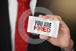 You are fired message on business card shown by a businessman. Labour force crisis Business risk management concept