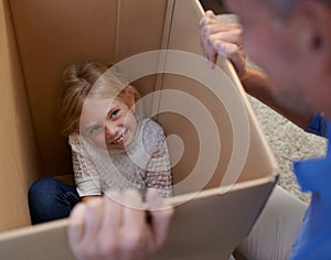 You found me. A young girl hiding in a box while playing with her father.