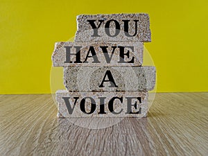 You have a voice symbol. Concept words You have a voice on brick blocks. Beautiful wooden table yellow background. Business,