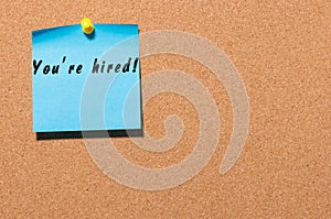 You are hired written on blue sticker pinned at notice board. Business concept with empty space for text