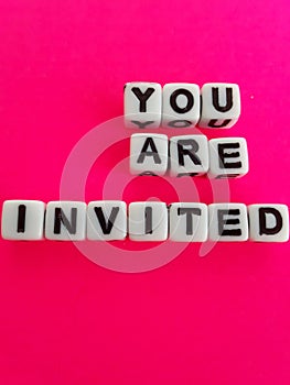 You are invited words letters on white blocks on a pink background