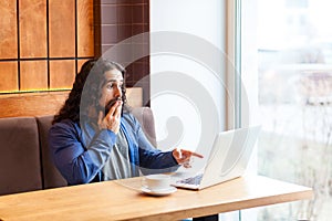 You kidding! Suprised young adult man freelancer in casual style sitting in cafe and talking with friendS in laptop, covering