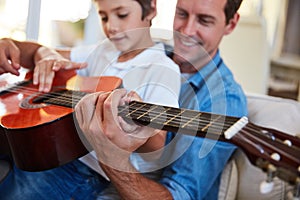 So you know this song. a father and his young son sitting together in the living room at home playing guitar.