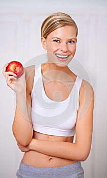 You know what they say about an apple a day...A portrait of a beautiful young woman eating a delicious red apple.