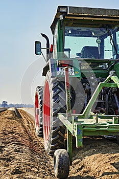 You look past a tractor at an asparagus field in Germany. The focus lies on the tire of the tractor, the horizon is somewhat out o