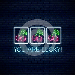 You are lucky - glowing neon motivation phrase with cherry on slot machine. Slot machine win combination with cherries