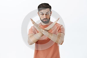 You must stop. Portrait of serious and confident bearded male friend showing cross with hands making not and prohibition