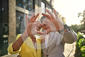 You are my heart. Portrait of cute and cheerful senior couple making a heart shape with their hands and fingers while