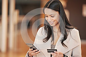 You never have to miss another bill. a young woman using her smartphone to make an online payment using her credit card.