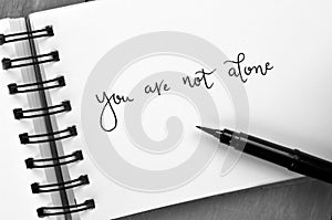 YOU ARE NOT ALONE hand-lettered in notepad