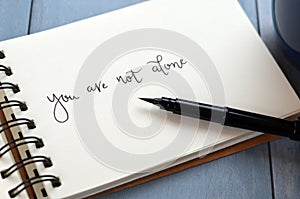 YOU ARE NOT ALONE hand-lettered in notepad