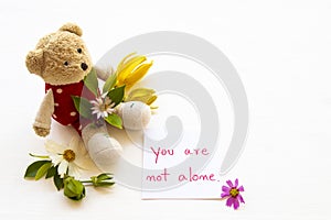 You are not alone message card handwriting with colorful flowers cosmos, ylang ylang and teddy bear