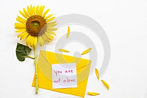 You are not alone message card handwriting in yellow envelope with yellow flower sunflower