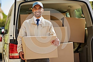 You order it, we deliver it. Portrait of a friendly delivery man unloading cardboard boxes from his van.