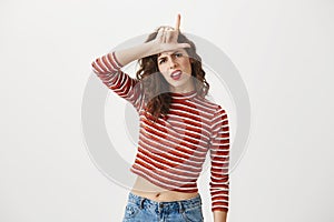 You are outsider. Studio shot of annoyed good-looking woman, feeling cool and confident while tilting head and showing