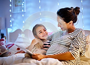 You picked a good one. Cropped shot of an attractive young pregnant woman reading her daughter a bedtime story on a