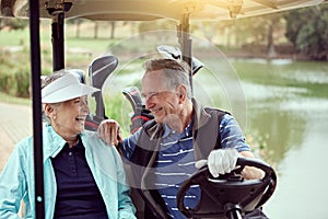 You played a great round. a smiling senior couple riding in a cart on a golf course.