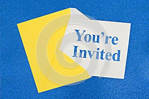You`re Invited message on white card with a yellow envelope photo