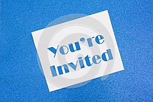You`re Invited message on white envelope on blue photo