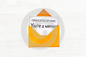 You`re a winner. Envelope with congratulation card on white wooden table top view