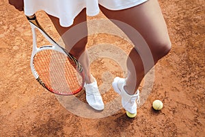 Are you ready to play? Cropped top view of a sporty young woman legs on clay tennis court with tennis balls on the ground. Sexy