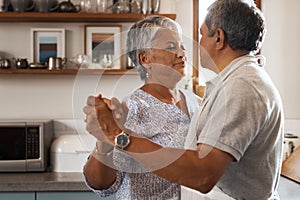 Are you ready to rock this retirement. a happy mature couple dancing together while cooking in the kitchen at home.