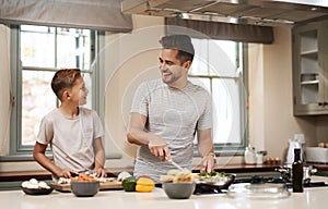 Are you ready to surprise mom with breakfast. a young boy helping his father cook in the kitchen.