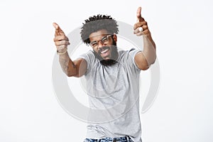 You rock man. Portrait of joyful good-looking emotive dark-skinned guy with afro hairstyle and beard pointing finger