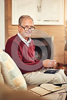 Are you a spender or a saver. a senior man working out a budget while sitting on the living room sofa.
