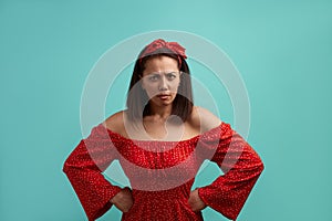 Are you thinking to joke on me. Portrait of angry strict young woman in red dress, standing with arms akimbo on waist