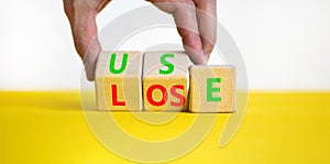 You use or lose it symbol. Concept word Use or lose on wooden cubes. Beautiful yellow table white background. Businessman hand.
