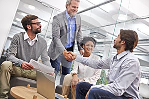 You've done well. Shot of a two business professionals shaking hands in an office.