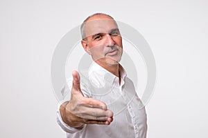 You are welcome concept. Cheerful mature man in white shirt gesturing welcome sign and smiling