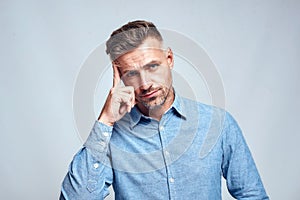 You Are What You Think. Portrait of young and smart bearded man in casual wear touching his head and looking at camera