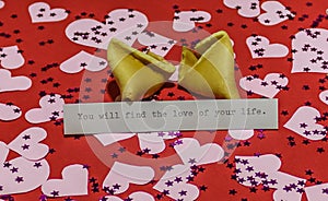 `You will find the love of your life` message in broken fortune cookie on red background covered with harts