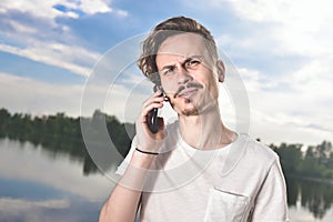 You will have problems man. Portrait of angry confused aggressive in bad mood guy irritably speaks on the phone on the background