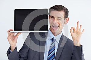 Youd be doing yourself a favor by getting this. A young businessman endorsing a laptop with an a okay hand sign. photo