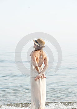 Youg calm dreaming woman standing alone near sea