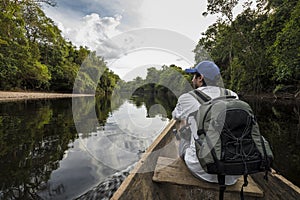 Youg man sitting onboard a canoe in the Amazon Jungle