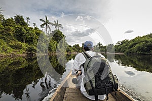 Youg man sitting onboard a canoe in the Amazon Jungle