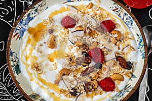Youghurt with granola, raspberry and honey on decorative plate