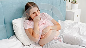 Yougn pregnant woman awake in the morning feeling unwell suffering from nausea. Intoxication during pregnancy